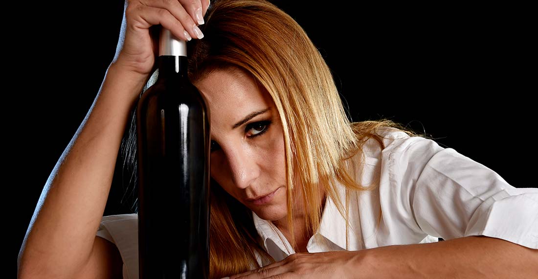 грустная женщина с бутылкой вина смотрит в камеру