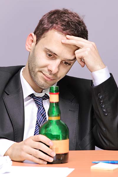 мужчина сидит за столом с бутылкой алкоголя
