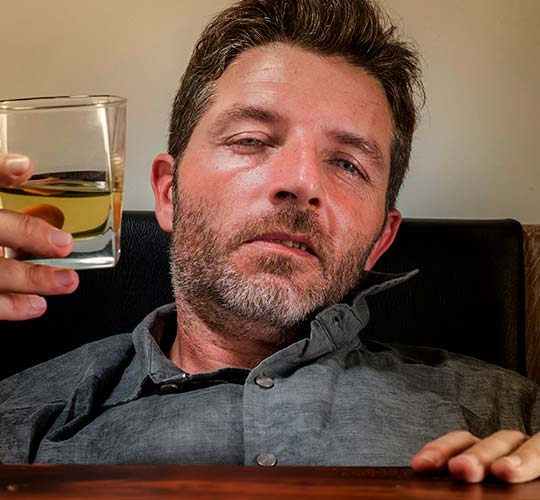 пьяный мужчина в рубашке со стаканом алкоголя